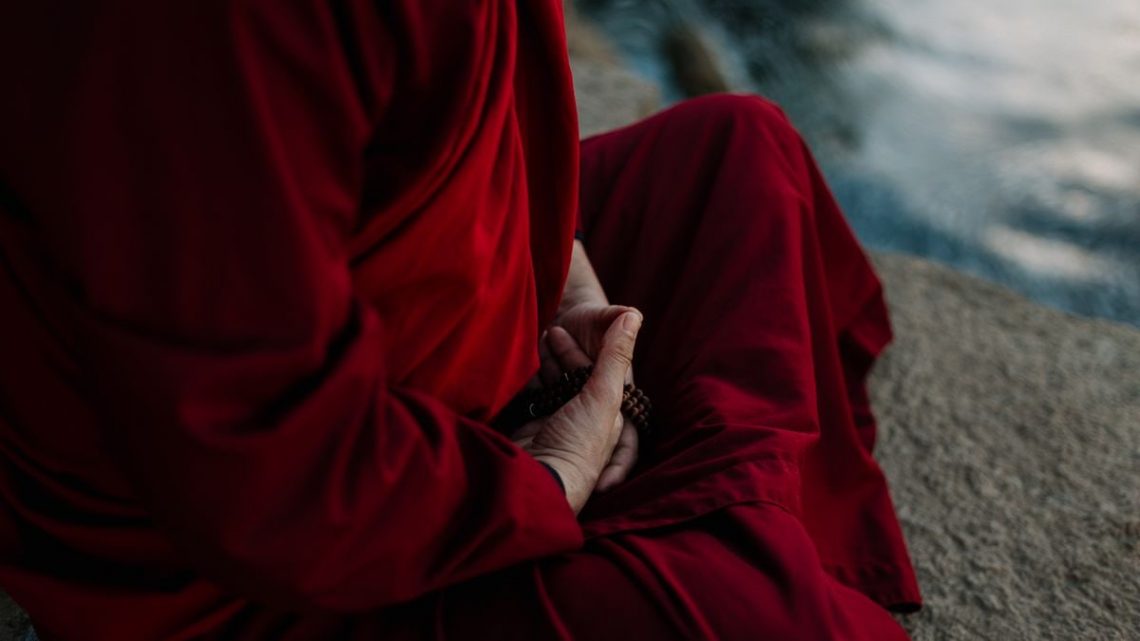 A monk in traditional robe holding prayer beads, embodying spirituality and tranquility.