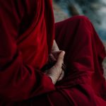 A monk in traditional robe holding prayer beads, embodying spirituality and tranquility.