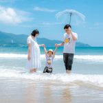 Happy family enjoying a sunny day at Da Nang Beach, Vietnam, playing in the waves.
