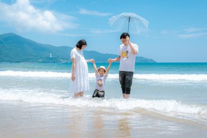 Happy family enjoying a sunny day at Da Nang Beach, Vietnam, playing in the waves.