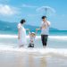 Happy family enjoying a sunny day at Da Nang Beach, Vietnam, playing in the waves.